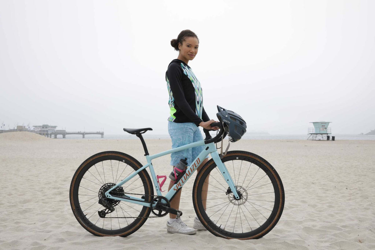Moxie Hoodie High Visibility Color Wave worn by cyclist on a beach with bike.