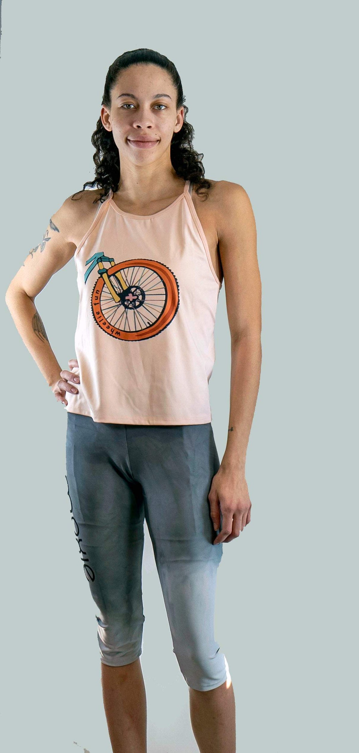 Woman wearing a tank top with a bicycle design and capri leggings on a plain background