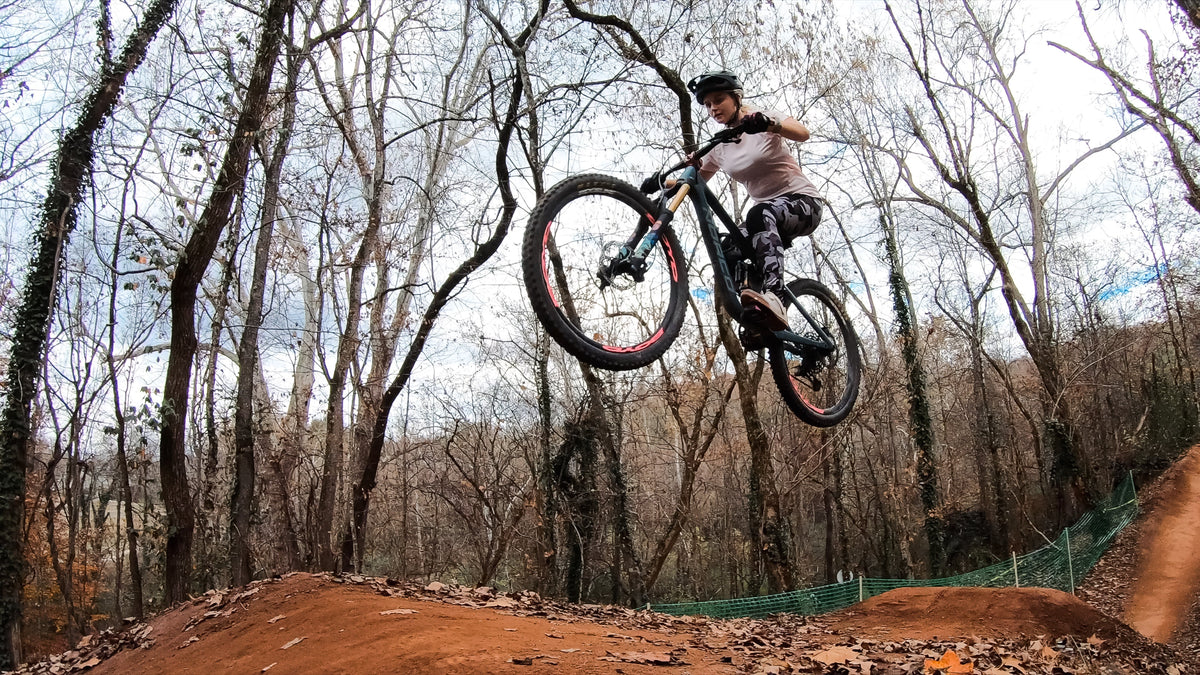 Moxie Cycling ambassador Lilly Diriver wearing Moxie Bike Pants while jumping her mountain bike