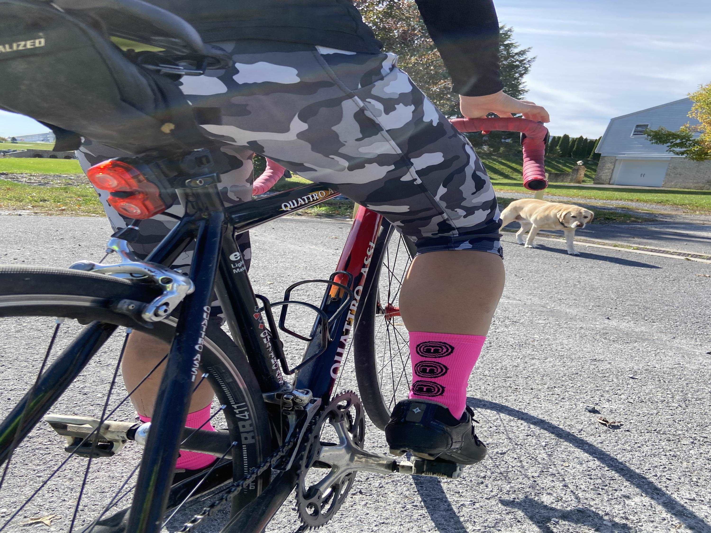 Cyclist wearing pink Hi Vis Moxie Socks with a 6-inch cuff on a road bike.