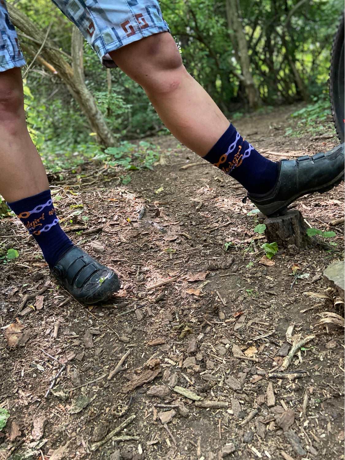 Moisture-wicking "Wicked Girl Socks" with 6-inch cuff, worn by a hiker in a forest setting.