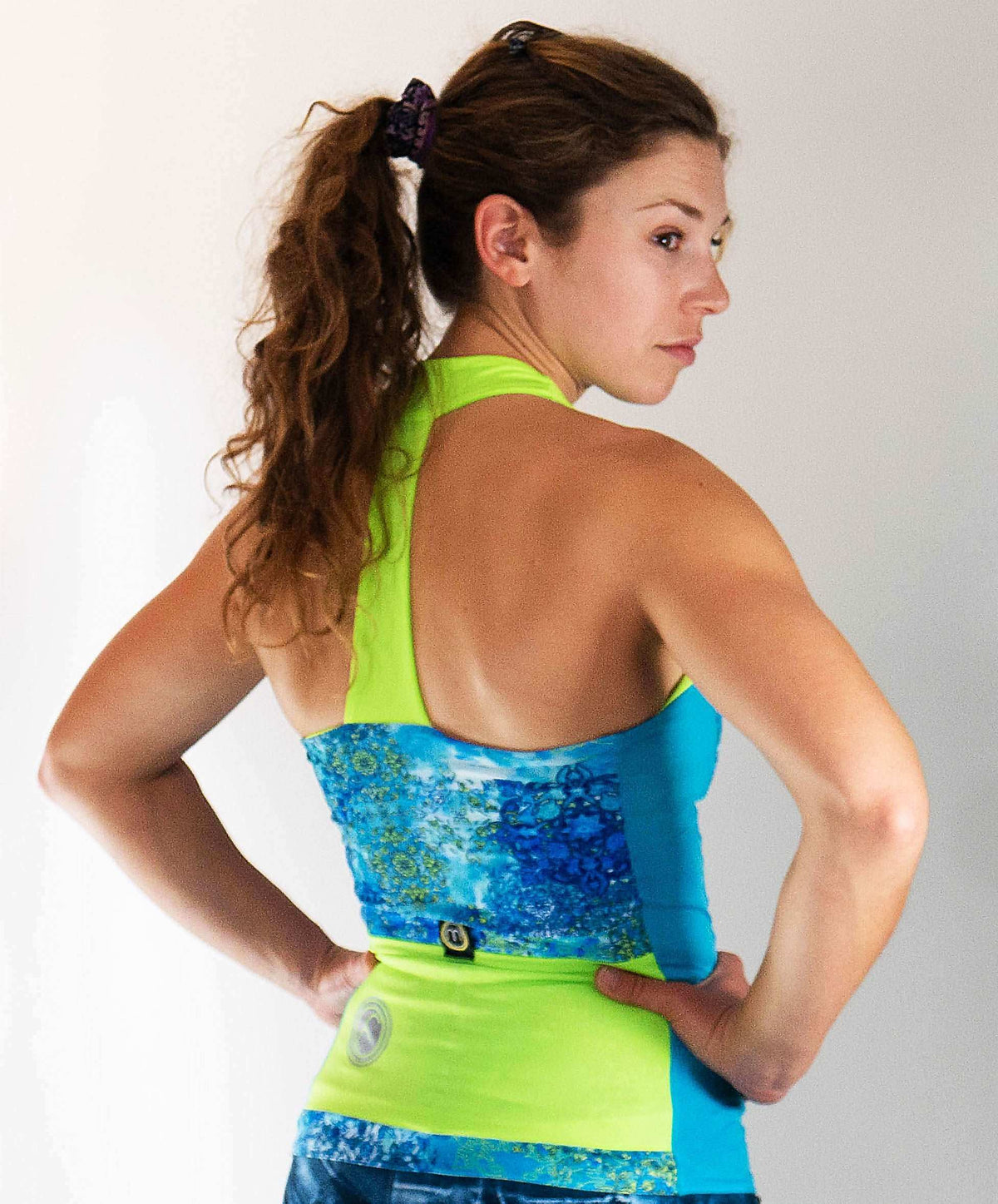 Sleeveless cycling jersey with T-back design in high visibility blue and green, showcasing a stylish fit and large pockets for comfort and functionality.