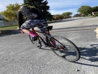 Cyclist wearing Moxie Socks in Moxie Yellow, riding a bicycle on a sunny day.