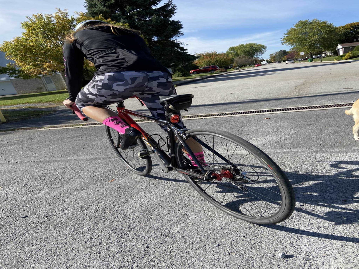 Cyclist wearing Moxie Socks in Moxie Yellow, riding a bicycle on a sunny day.