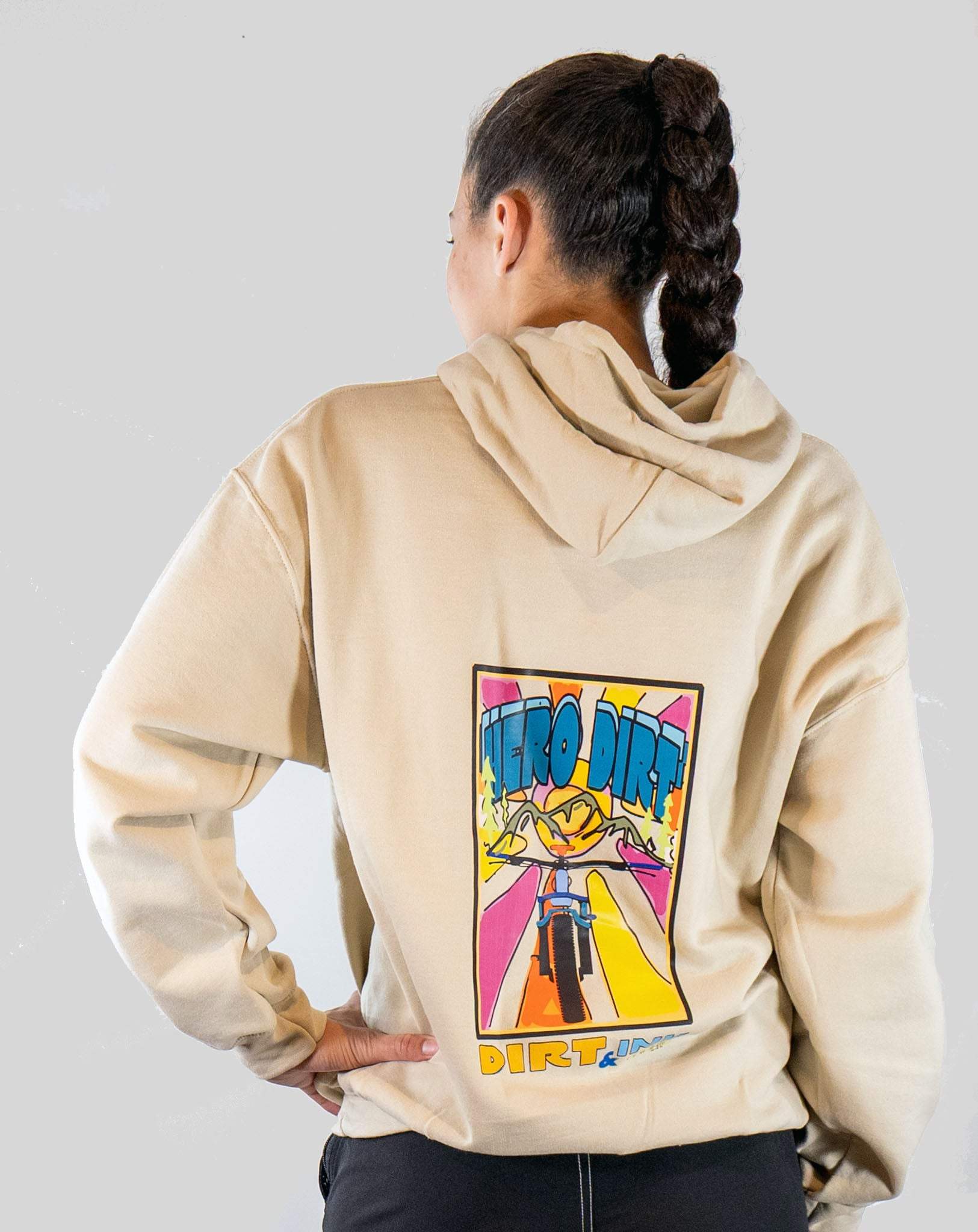 Person wearing a beige hoodie with a colorful graphic on the back against a plain background