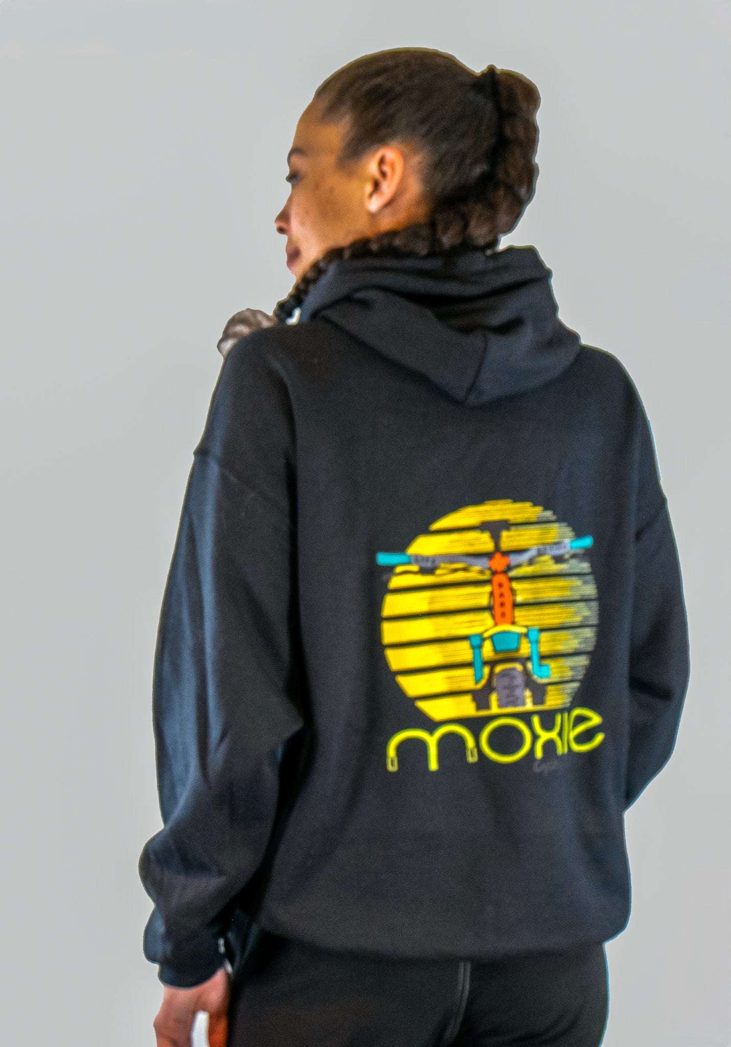Person wearing a black hoodie with a colorful graphic on the back against a gray background