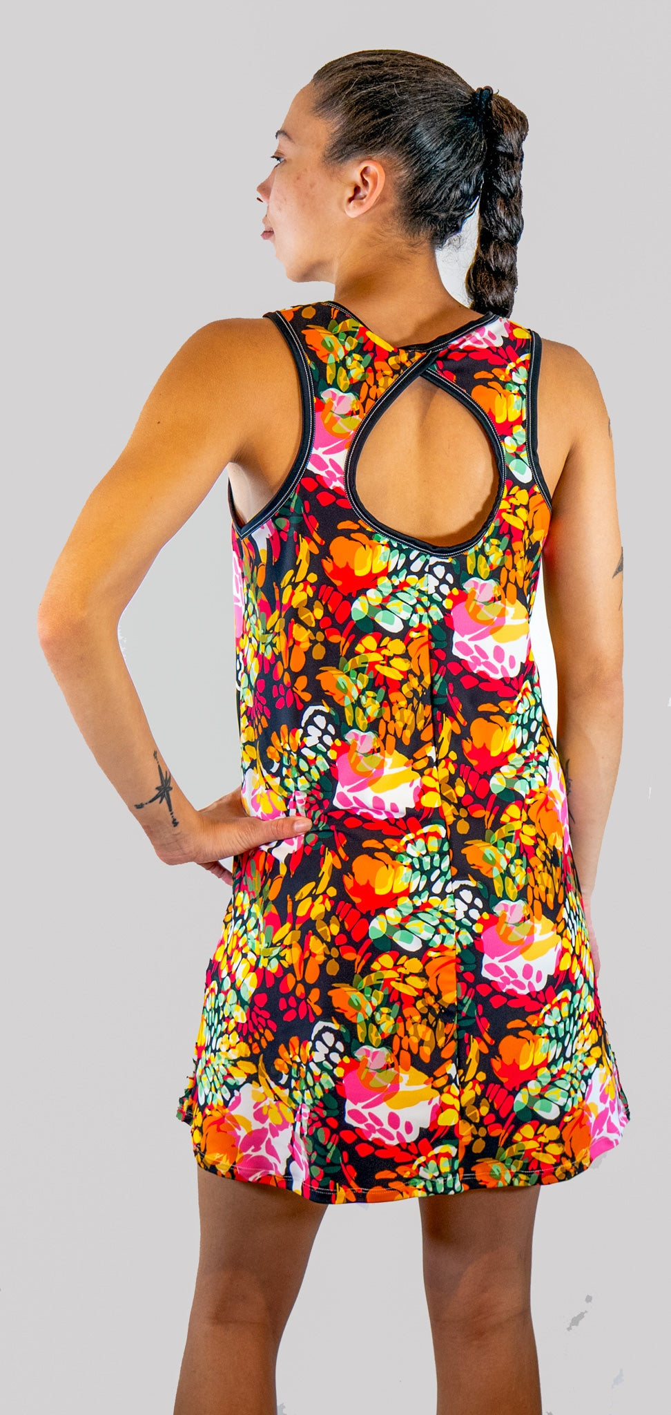 Woman wearing a colorful floral dress on a plain background