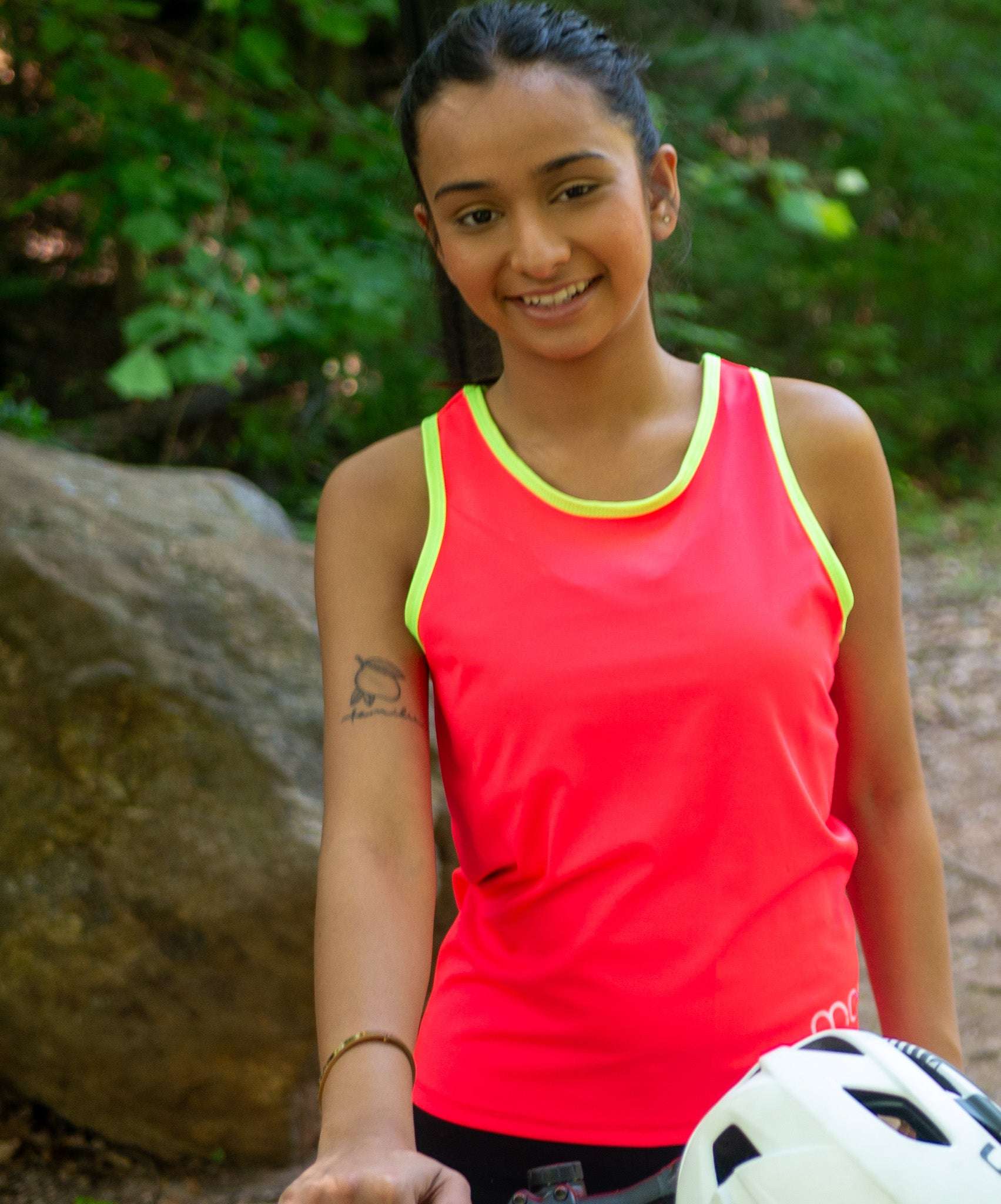 Woman in a high visibility cycling tank top next to her gravel bike