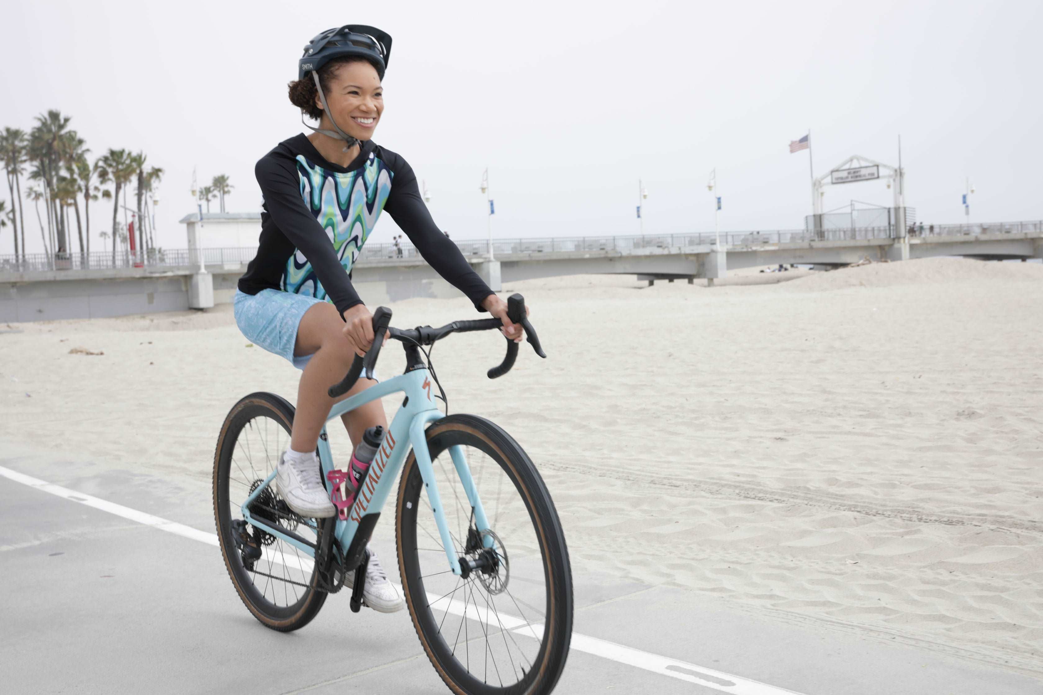 Woman riding a bike wearing blue mountain bike shorts with comfortable fit and chamois on a scenic path.