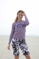 Women's mountain bike shorts with yin-yang design, comfortable waistband, versatile pockets, and purple stitching, beach background.