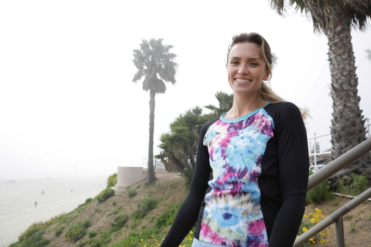 Moxie Tee Jersey Kon Tiki long sleeve in vibrant floral design worn by a smiling woman outdoors.