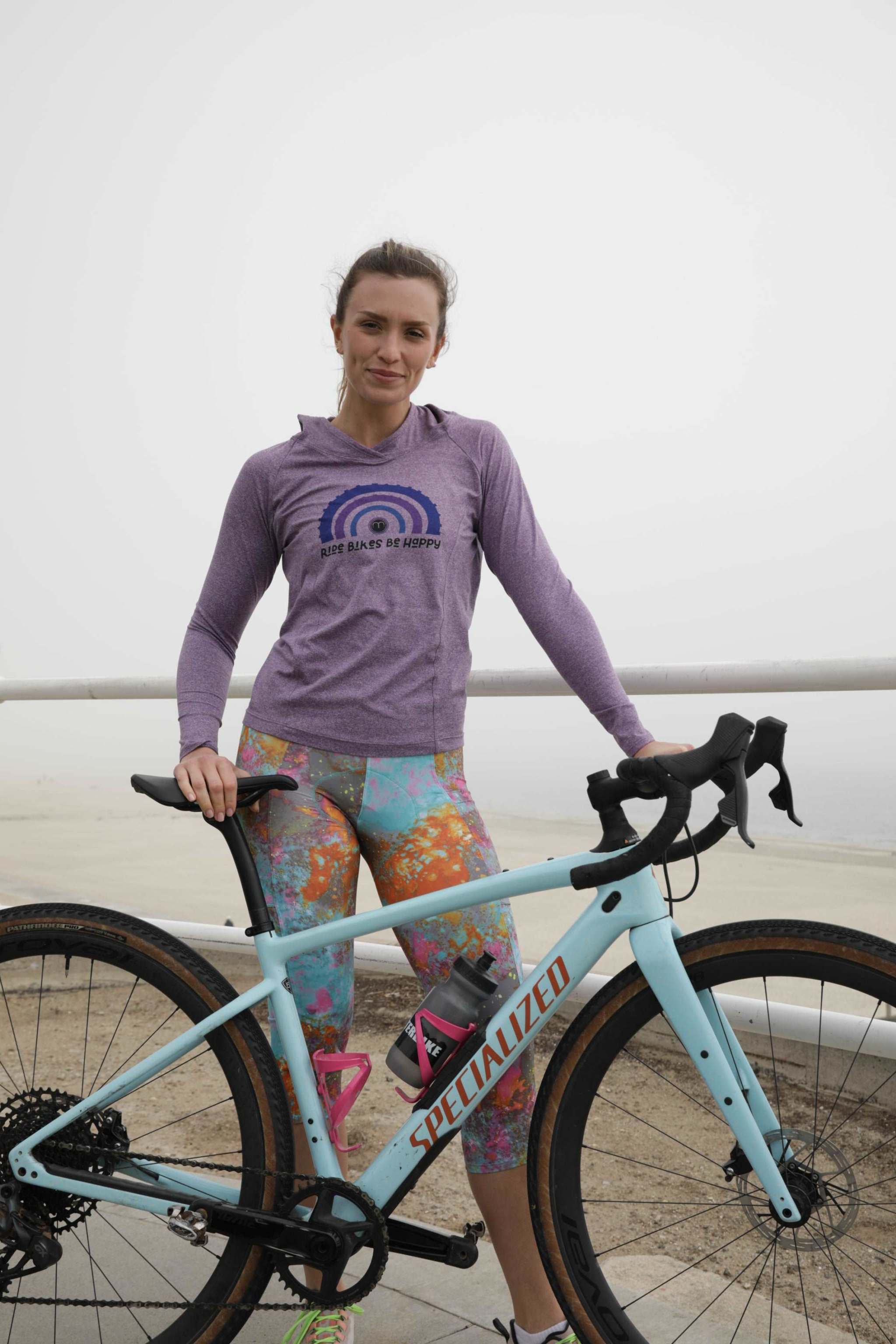 Cyclist wearing colorful cycling knickers with floral design, standing with a bicycle.