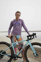 Cyclist wearing colorful cycling knickers with floral design, standing with a bicycle.