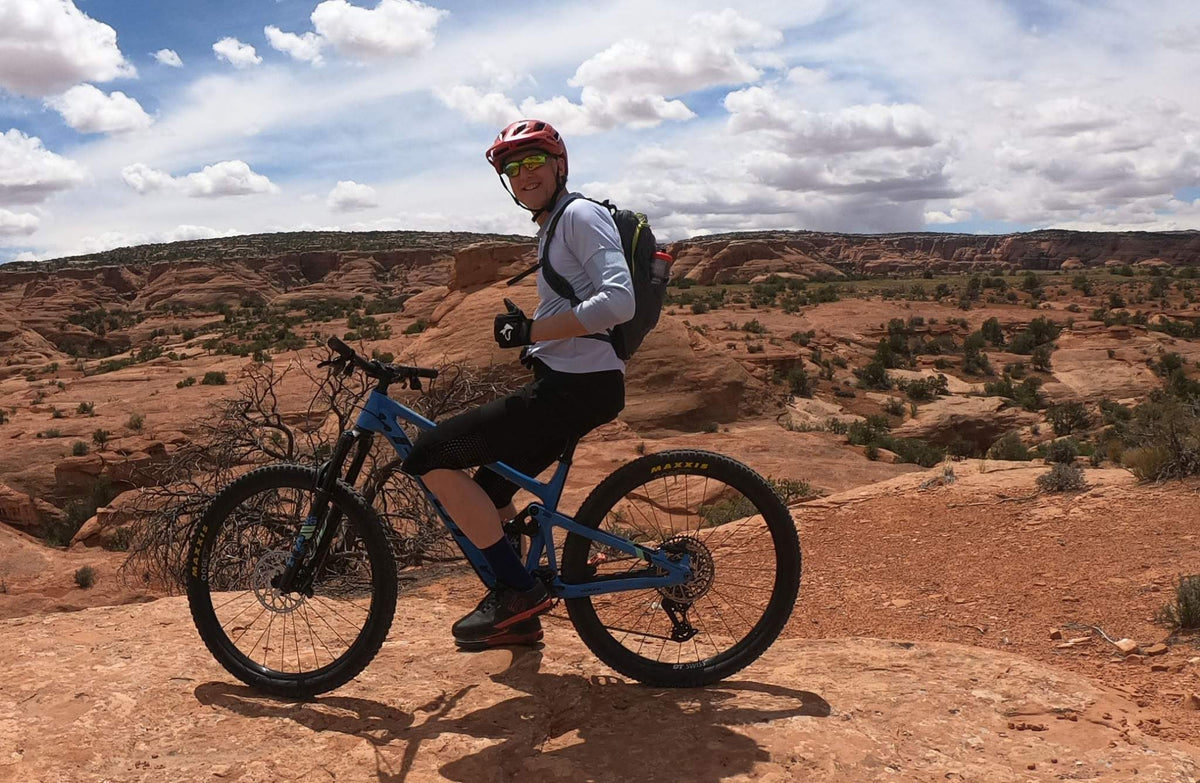 Person with a blue mountain bike in a desert landscape