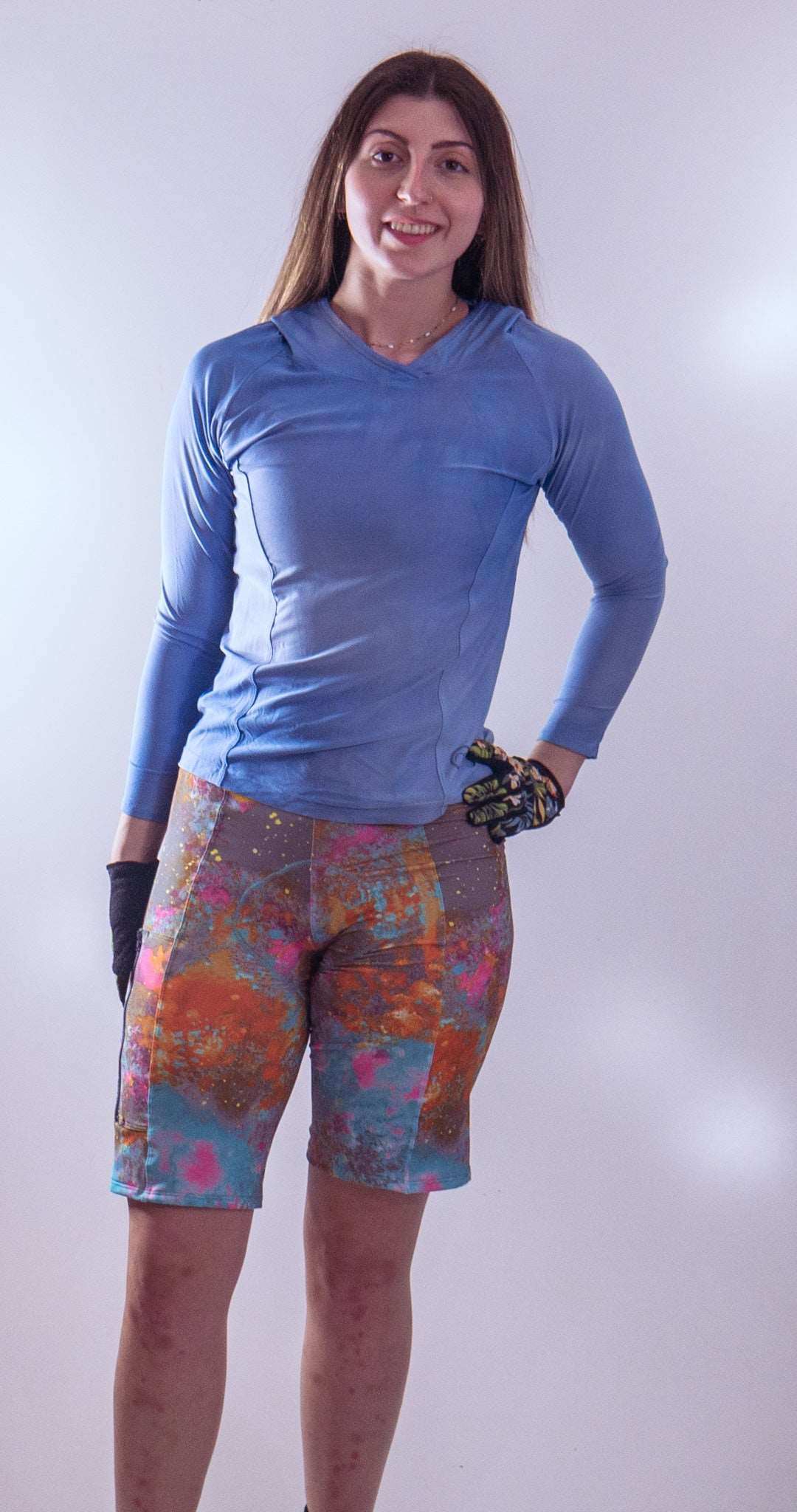 Woman wearing Steezy Stretch Bike Shorts Wild Fire with a colorful abstract pattern and a blue long-sleeve top