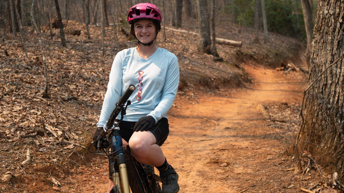 Moxie Sun Saver Hoodie on cyclist in forest trail.