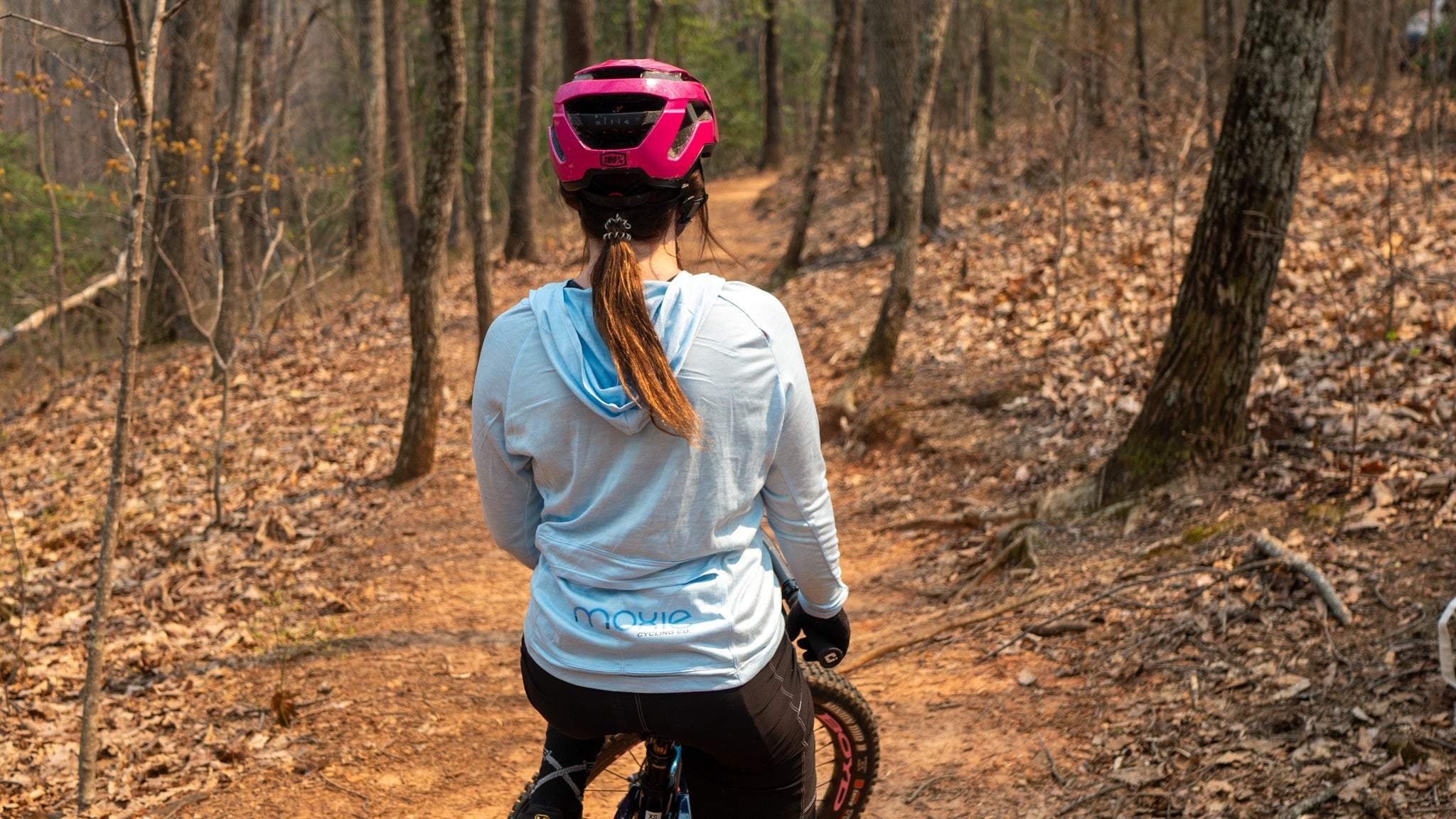 Moxie Sun Saver Hoodie with bike cog graphic in a wooded trail setting.