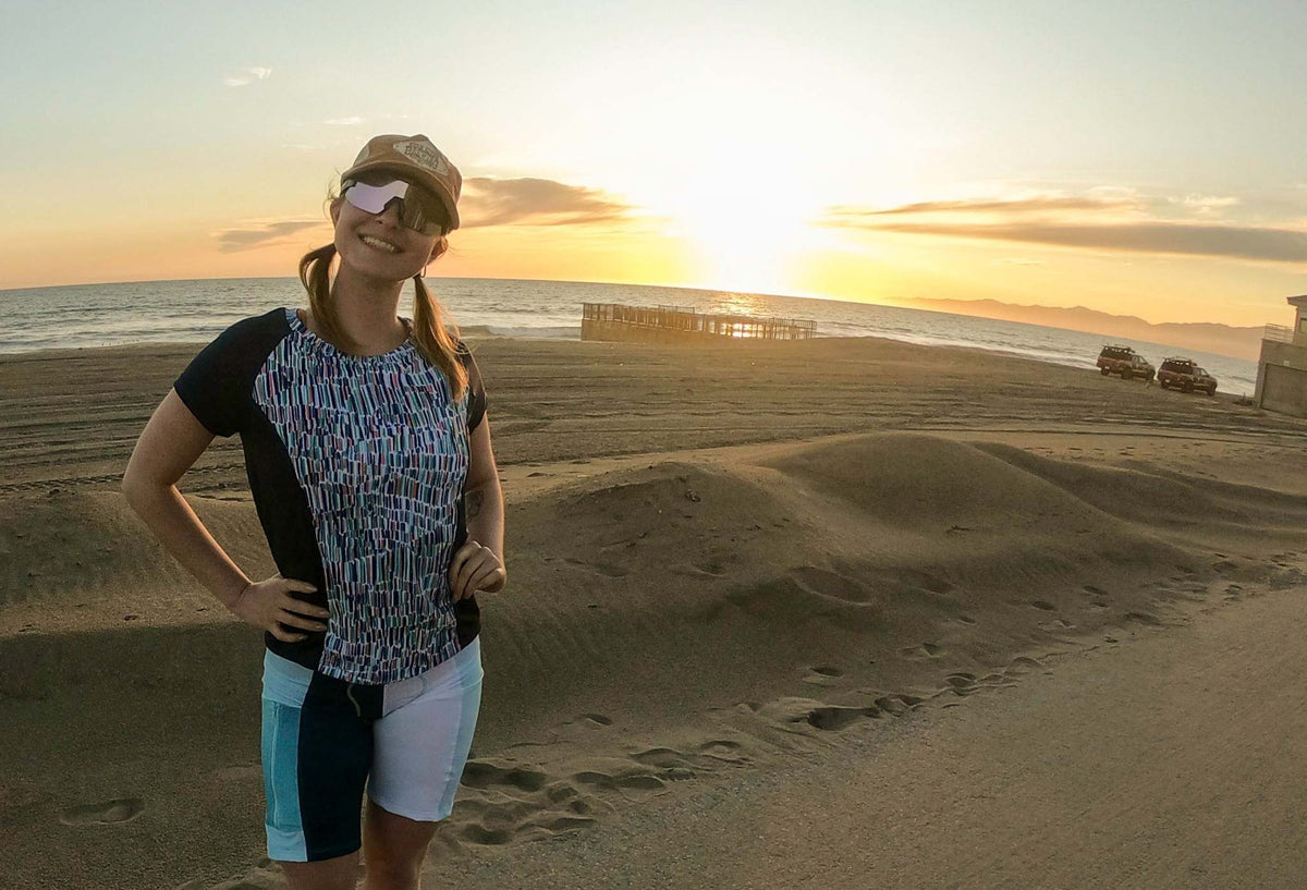 Moxie Tee Jersey Blues long sleeve biking shirt worn by woman at sunset beach.