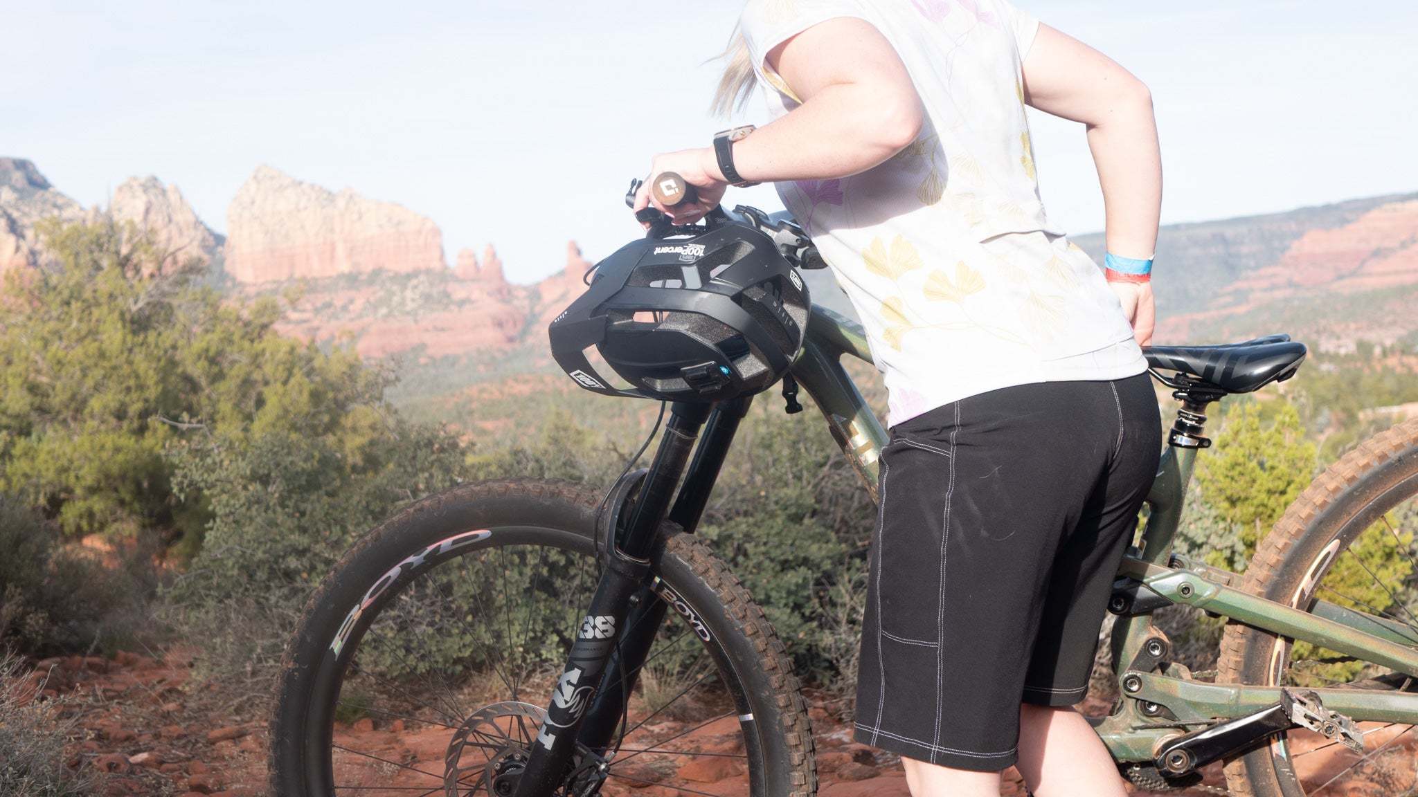 Woman wearing Moxie Tee Jersey Moss Floral standing next to mountain bike in outdoor trail setting