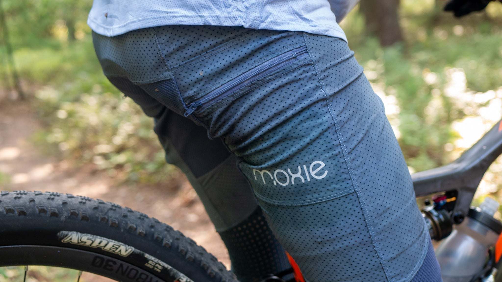 Cyclist wearing Trail Pants with removable G-Form knee pads on a bike in the woods.