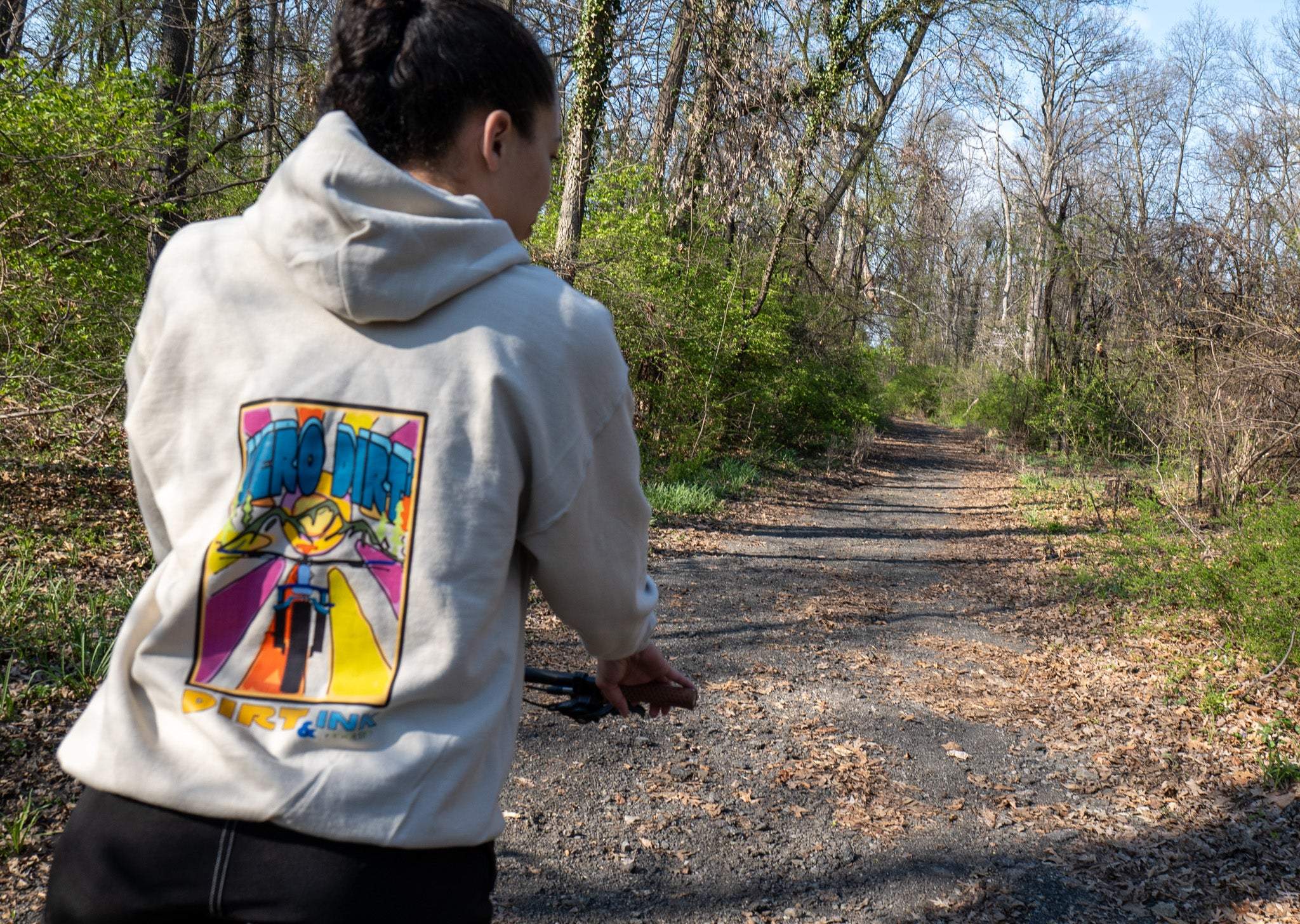Person wearing a hoodie with a colorful graphic on a forest path
