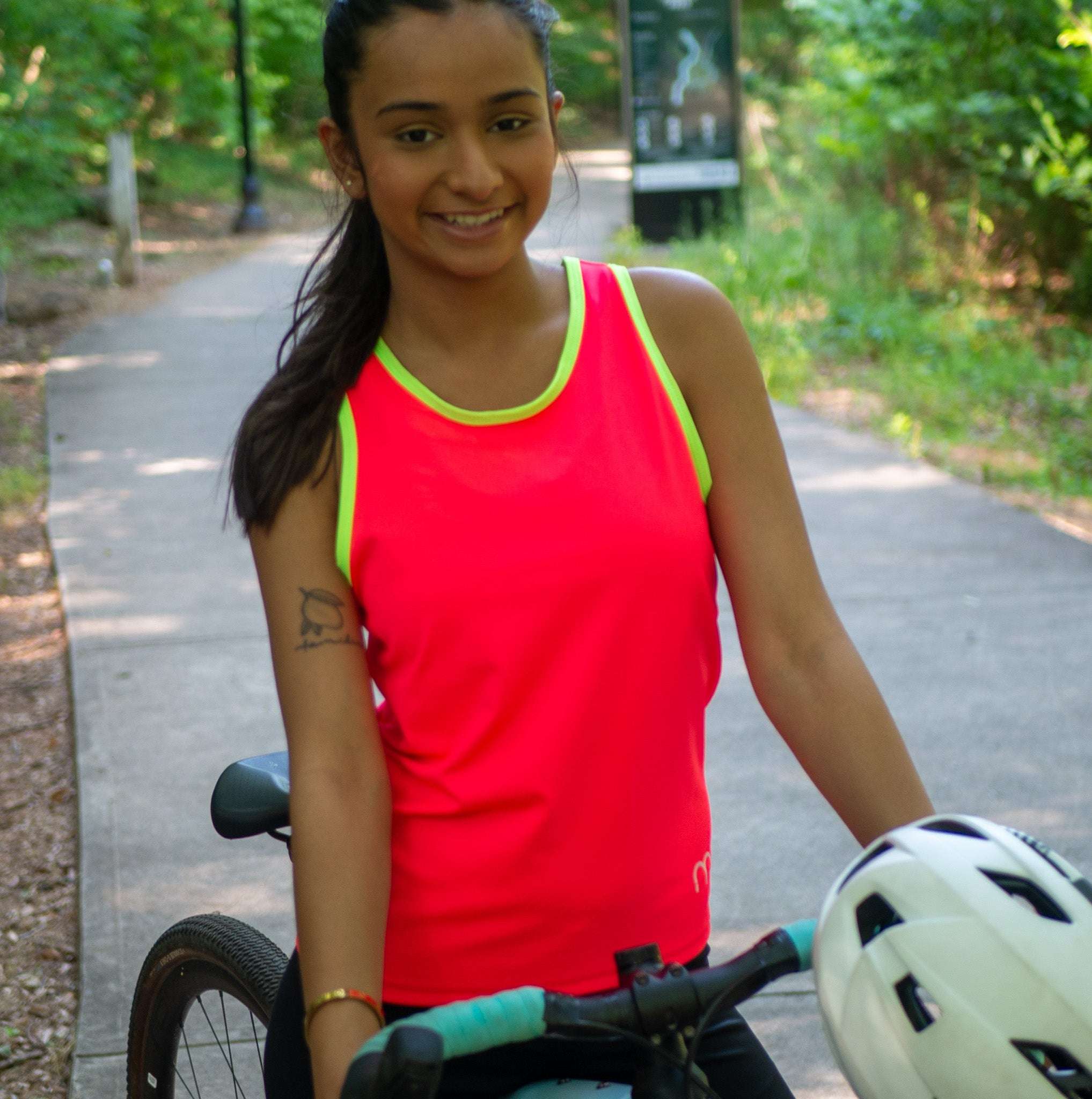 Woman in a high visibility cycling tank top next to her gravel bike
