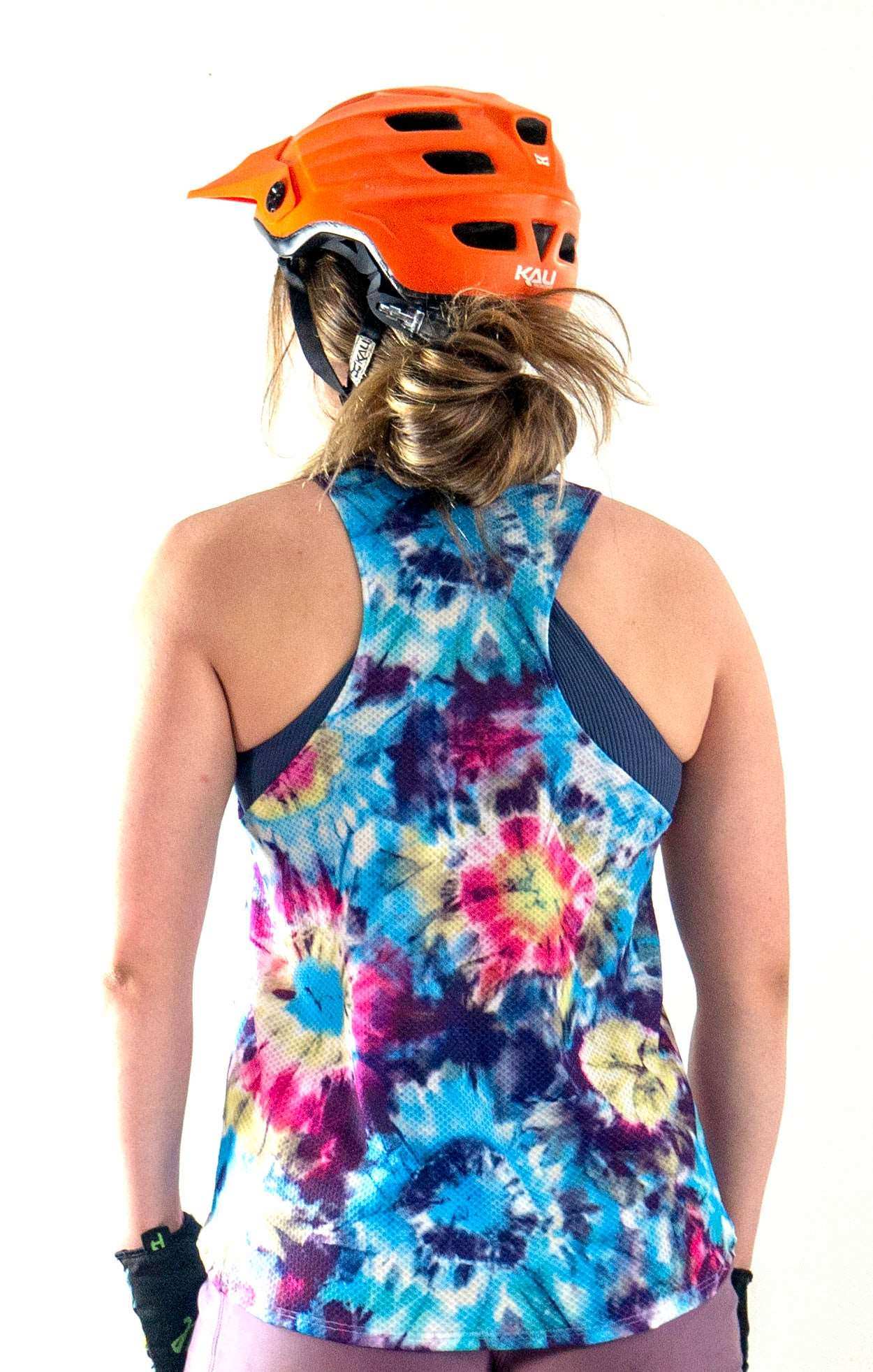 woman wearing swifly tech tank in colorful tie-dye design with orange helmet, showcasing breathable lightweight fabric suitable for sporty activities