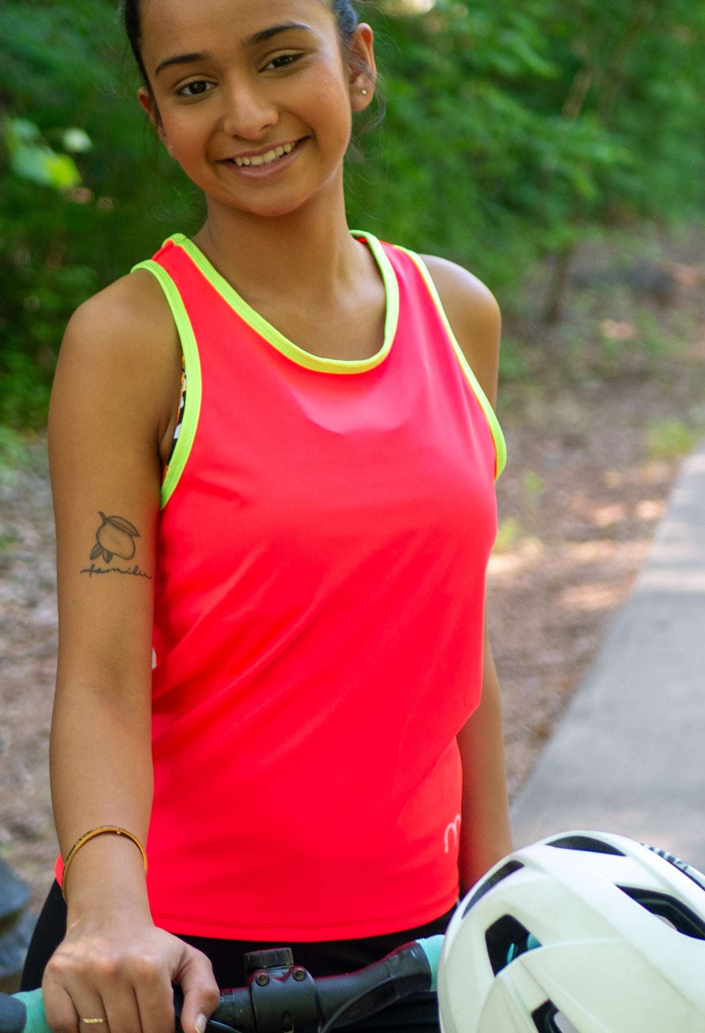 Woman in a high visibility cycling tank top next to her gravel bike