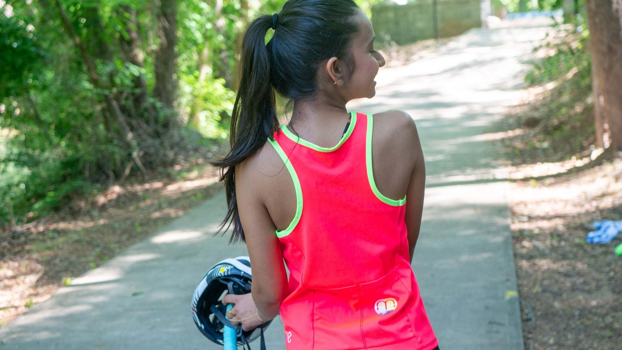 Women in a high vis tank cycling jersey on her gravel bike view is from the back