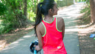 Women in a high vis tank cycling jersey on her gravel bike view is from the back