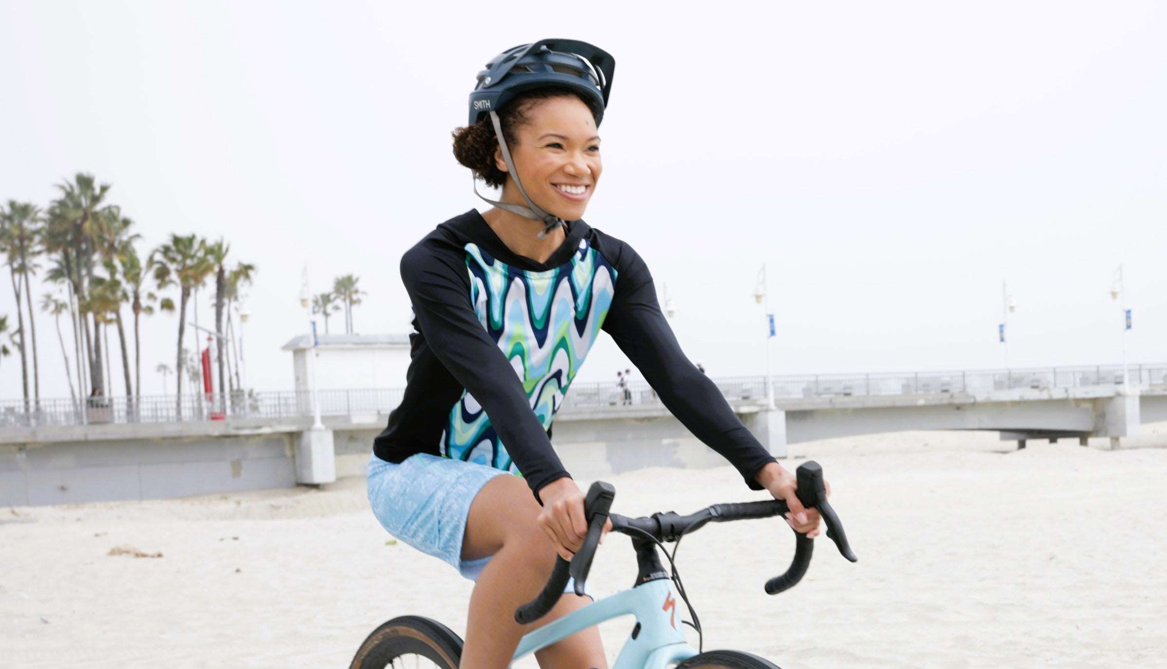 Cyclist wearing Moxie Tee Long Sleeve Jersey Color Wave on a beach ride.