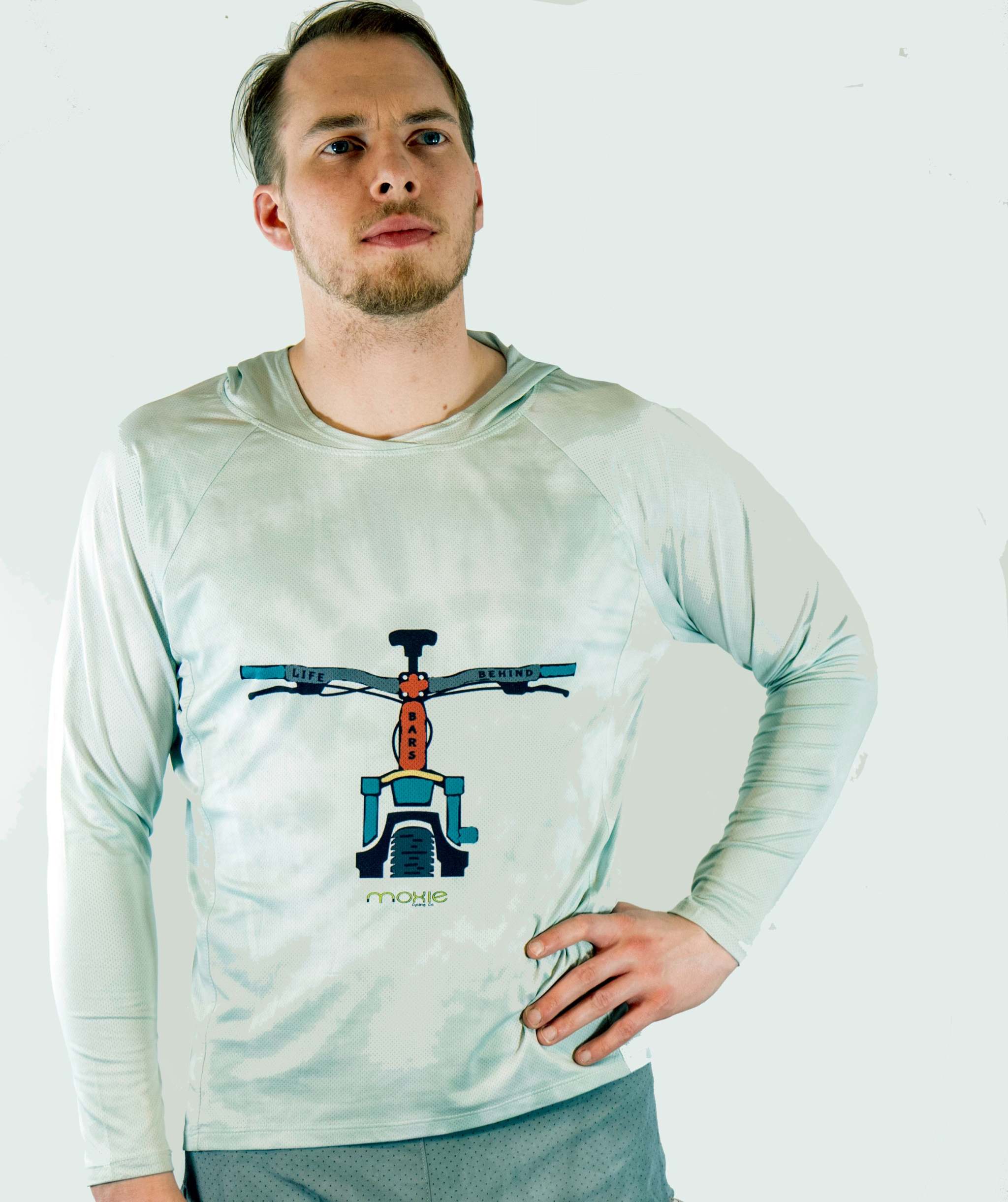 Man wearing a light green long-sleeve shirt with a bicycle graphic on a white background