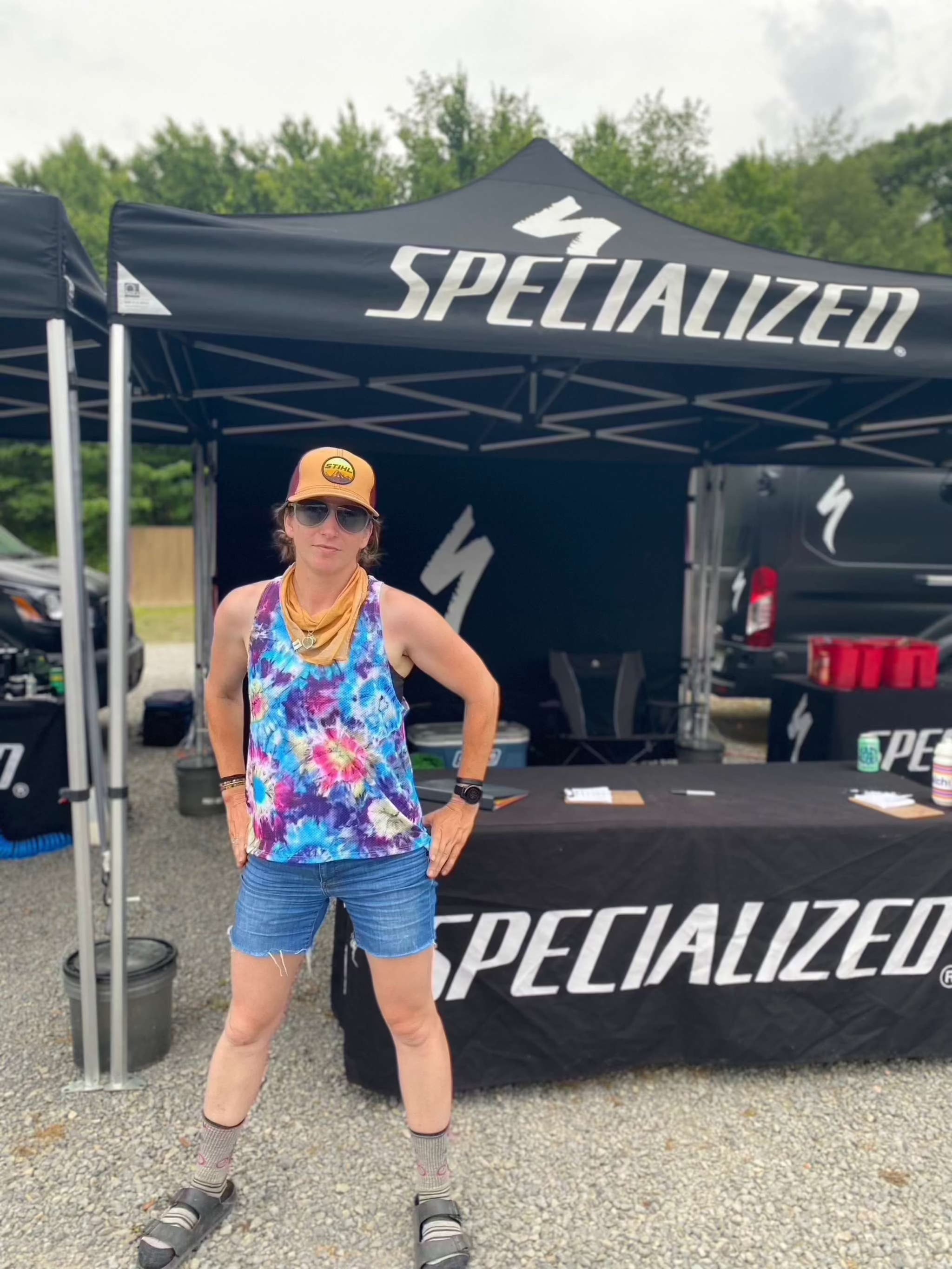 swifly tech tank with breathable lightweight sporty design worn at an outdoor event with Specialized tents in the background.