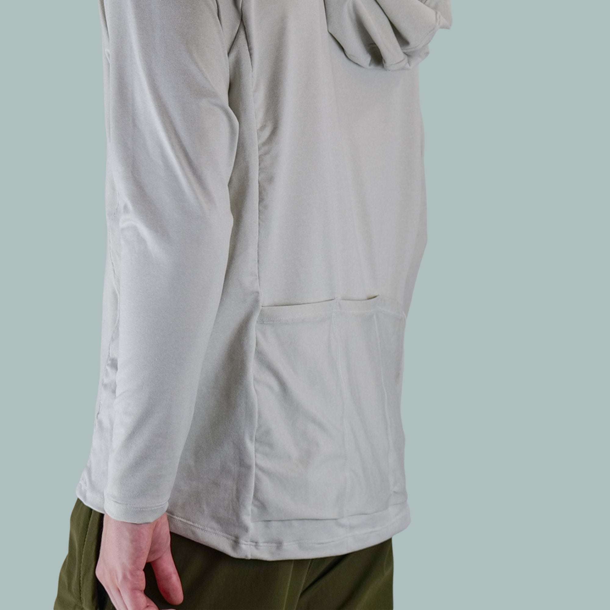 Men's Fall Cycling Hoodie in light gray with long sleeves, a back pocket, and a hood, paired with olive green pants.
