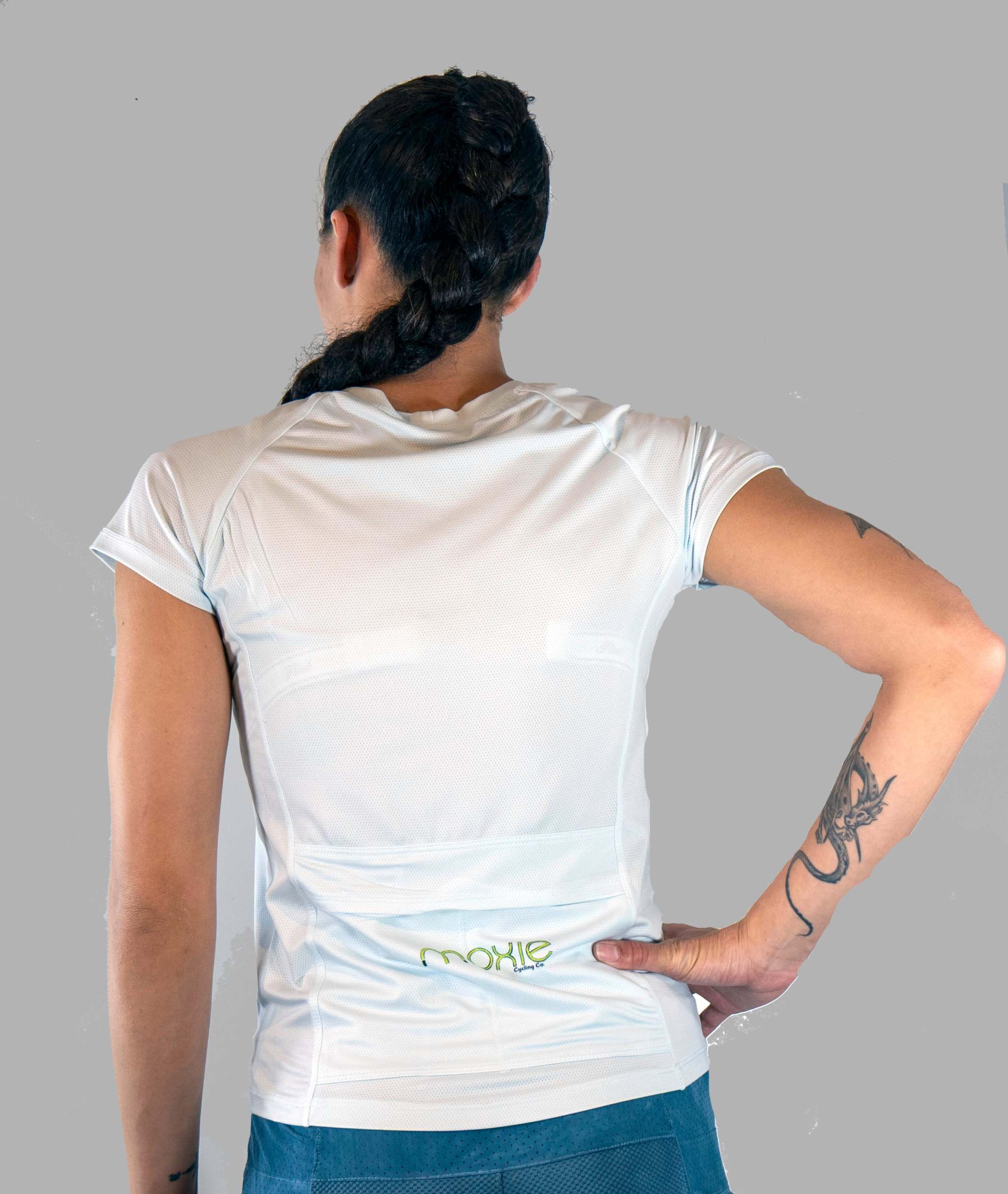 Person wearing a white t-shirt with text on the back, standing against a gray background