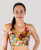 Woman wearing a colorful floral sports bra against a plain background
