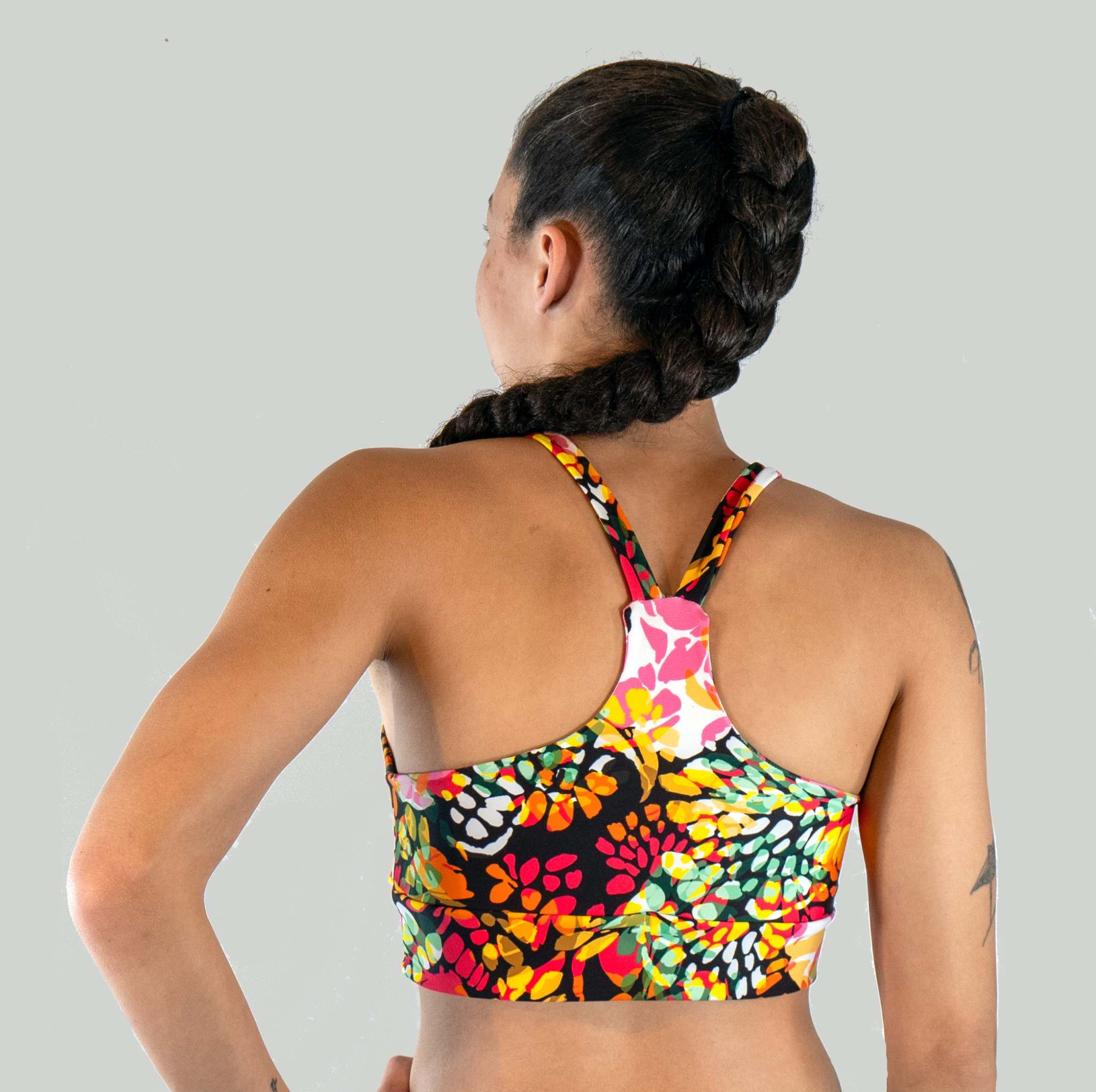 Woman wearing a colorful floral sports bra on a plain background
