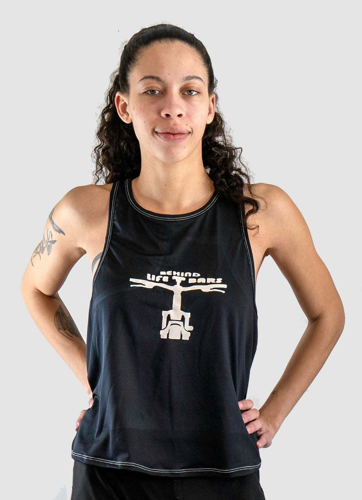 Woman wearing Moxie Tech Tank breathable mesh cycling jersey with "Ride Bikes Be Happy" graphic on summer ride