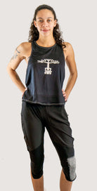 Woman wearing Moxie Tech Tank breathable mesh cycling jersey with "Life Behind Bars" graphic on mountain bike trail