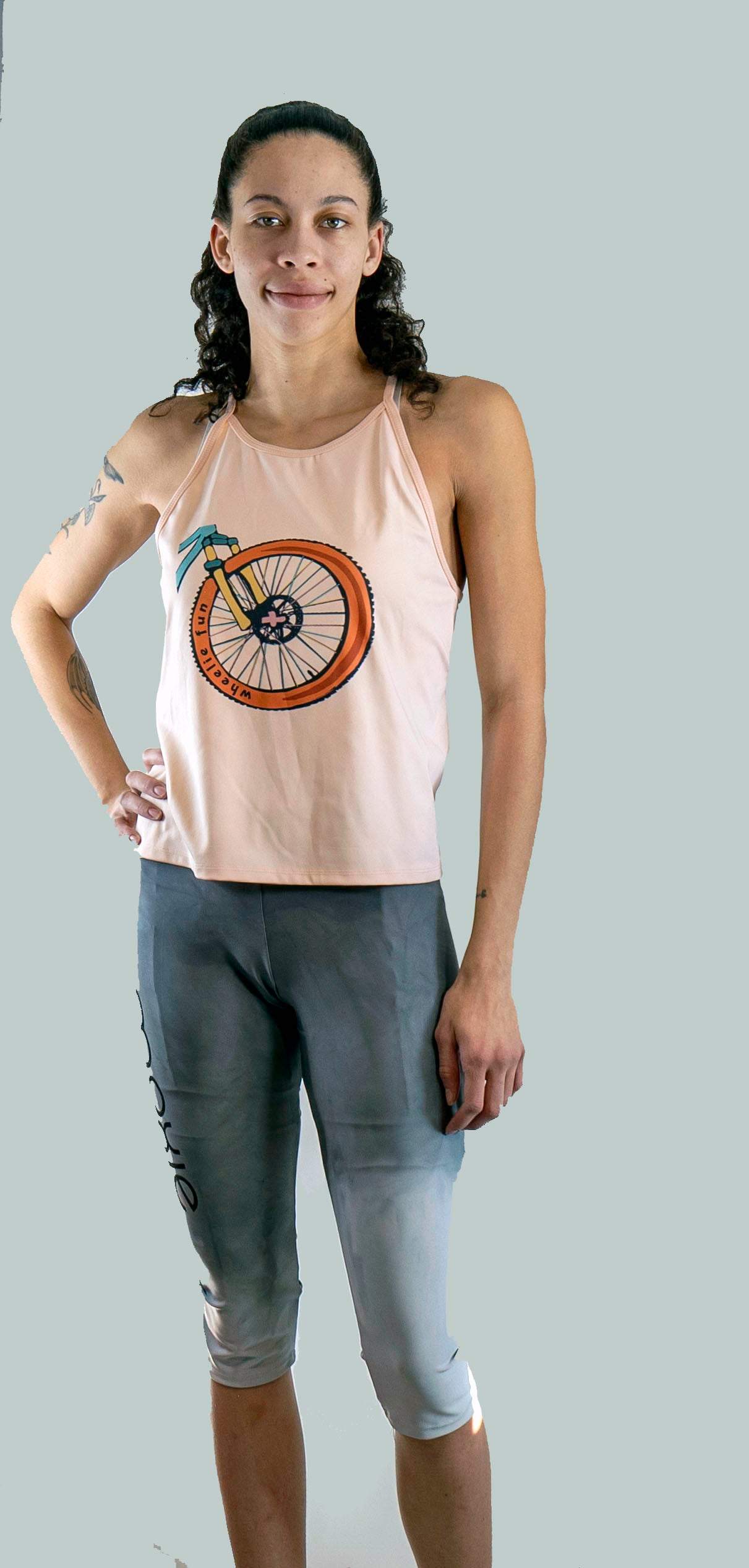 Woman wearing a tank top with a bicycle design and capri leggings on a plain background